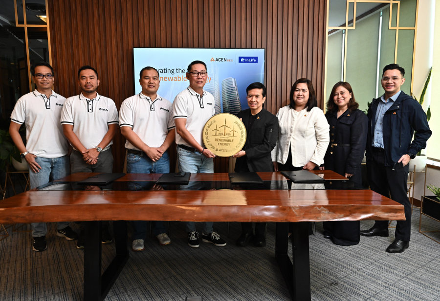A group of representatives from InLife and ACEN RES stand together holding a large circular “Renewable Energy” badge during a ceremonial partnership event, with a digital display showing both companies’ logos in the background.